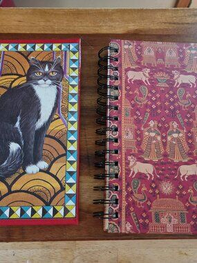 notebooks one with a cat motif and other with Indian pichwai art both have paper
